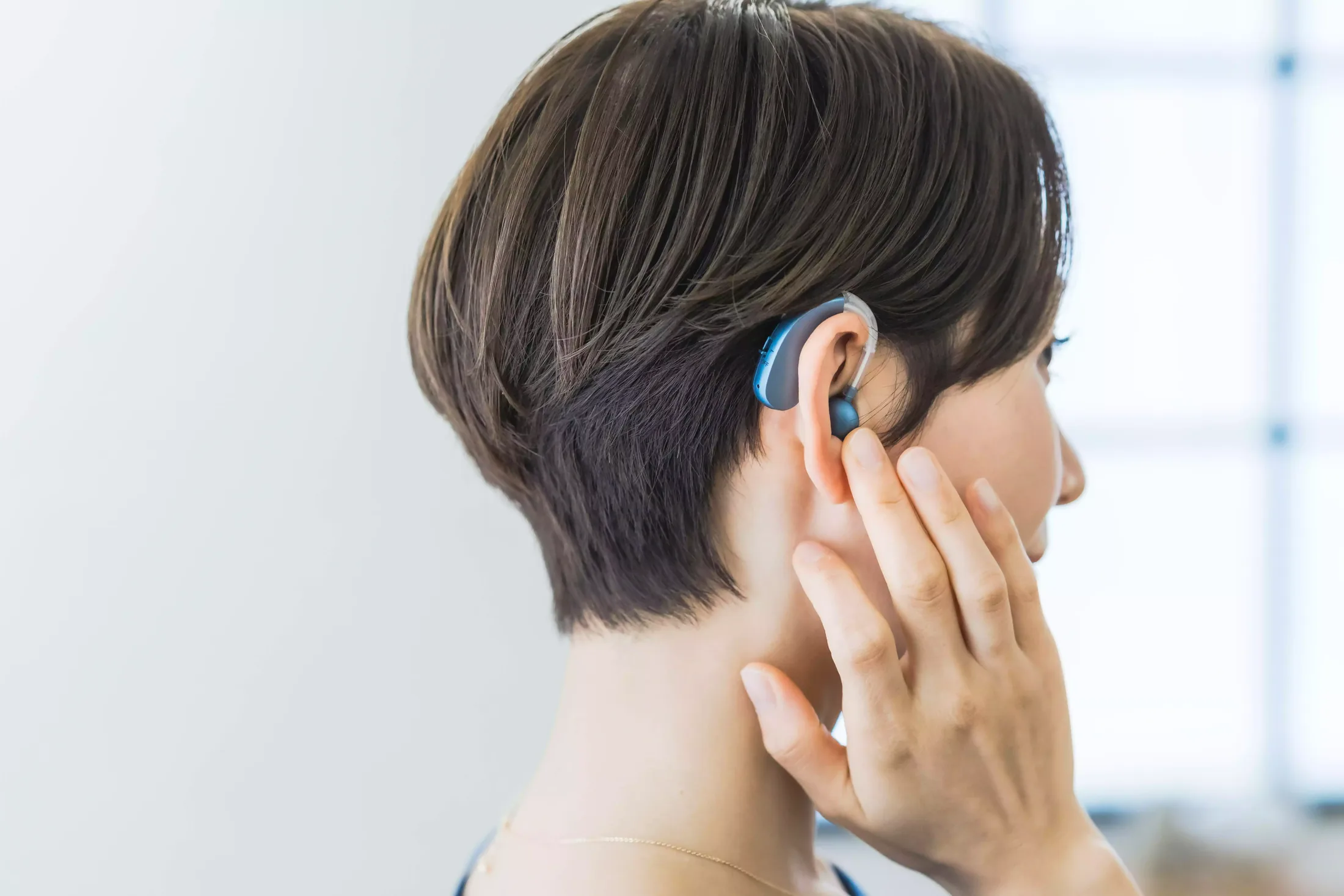 Femme portant la main à son oreille pour mieux entendre